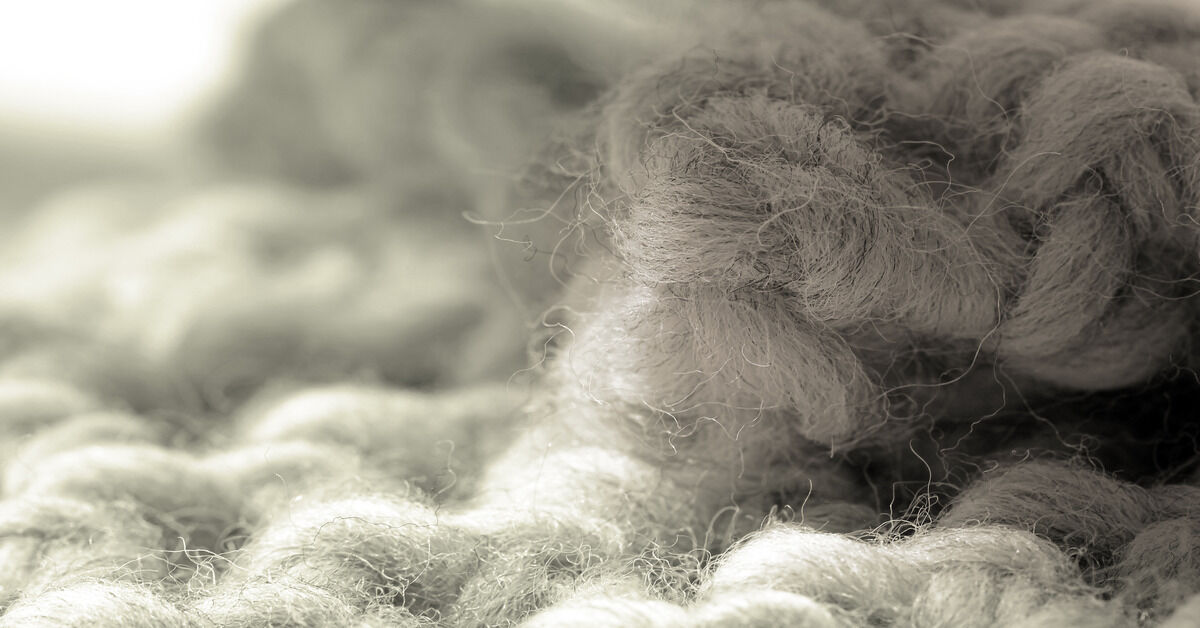 A close-up of white and grey wool cotton fibers woven together.